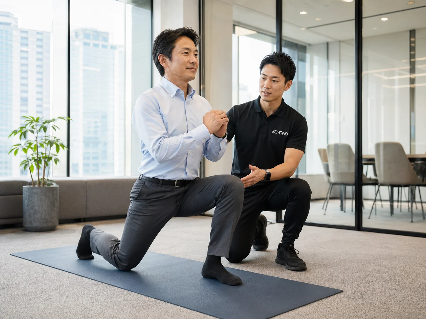 オフィス会議室でトレーナーと1対1でトレーニングするスーツ姿の男性