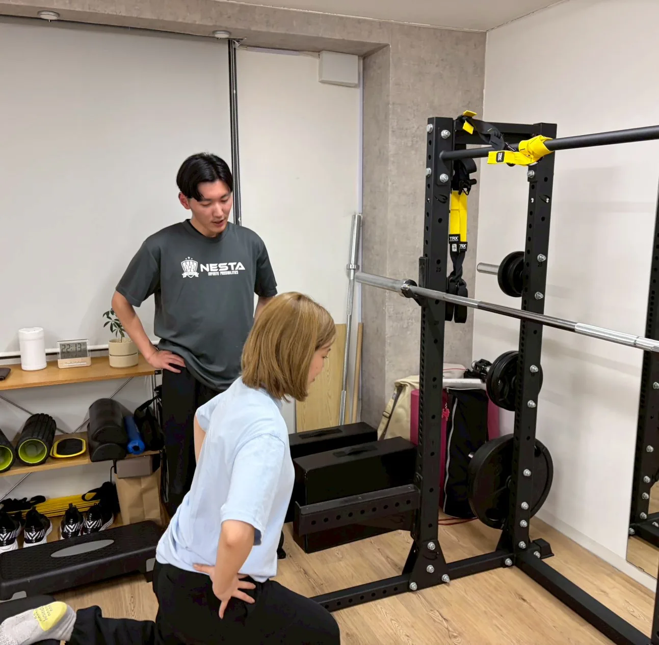 スクワット動作をトレーナーが見守っている様子