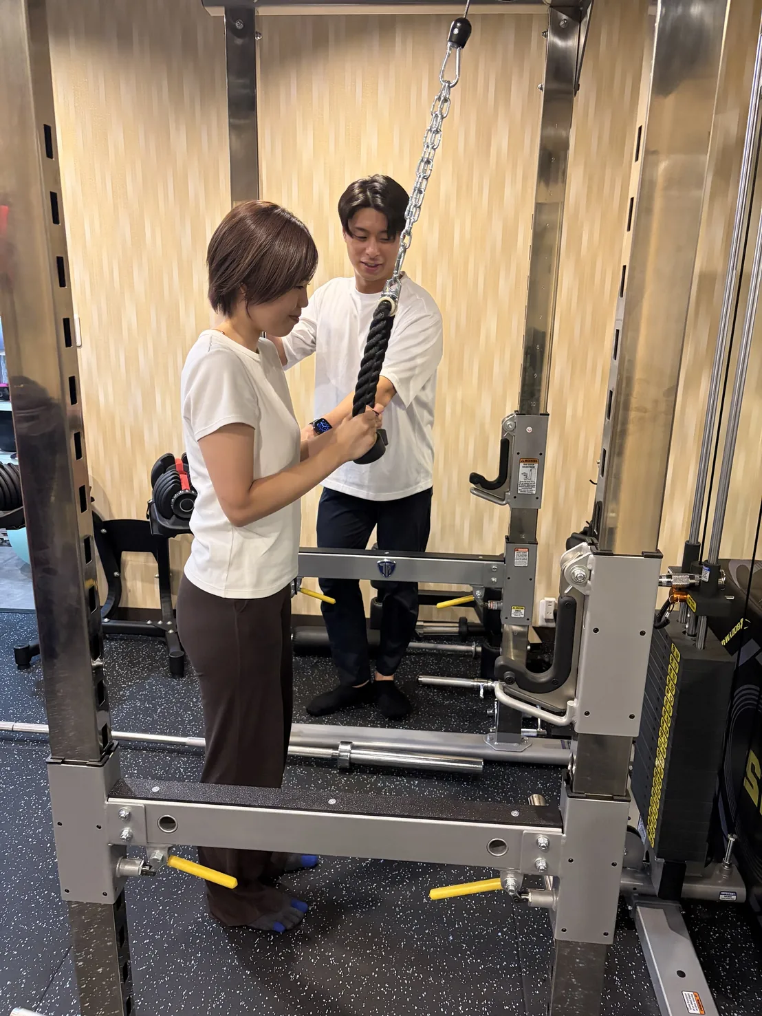 FIT STAGEのトレーナーが、ケーブルマシンを使った種目のフォームを確認する様子