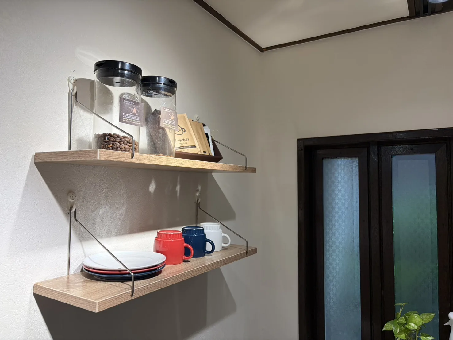 厳選したスペシャルティコーヒーの豆とマグカップが並ぶ棚 — FIT STAGE江坂店