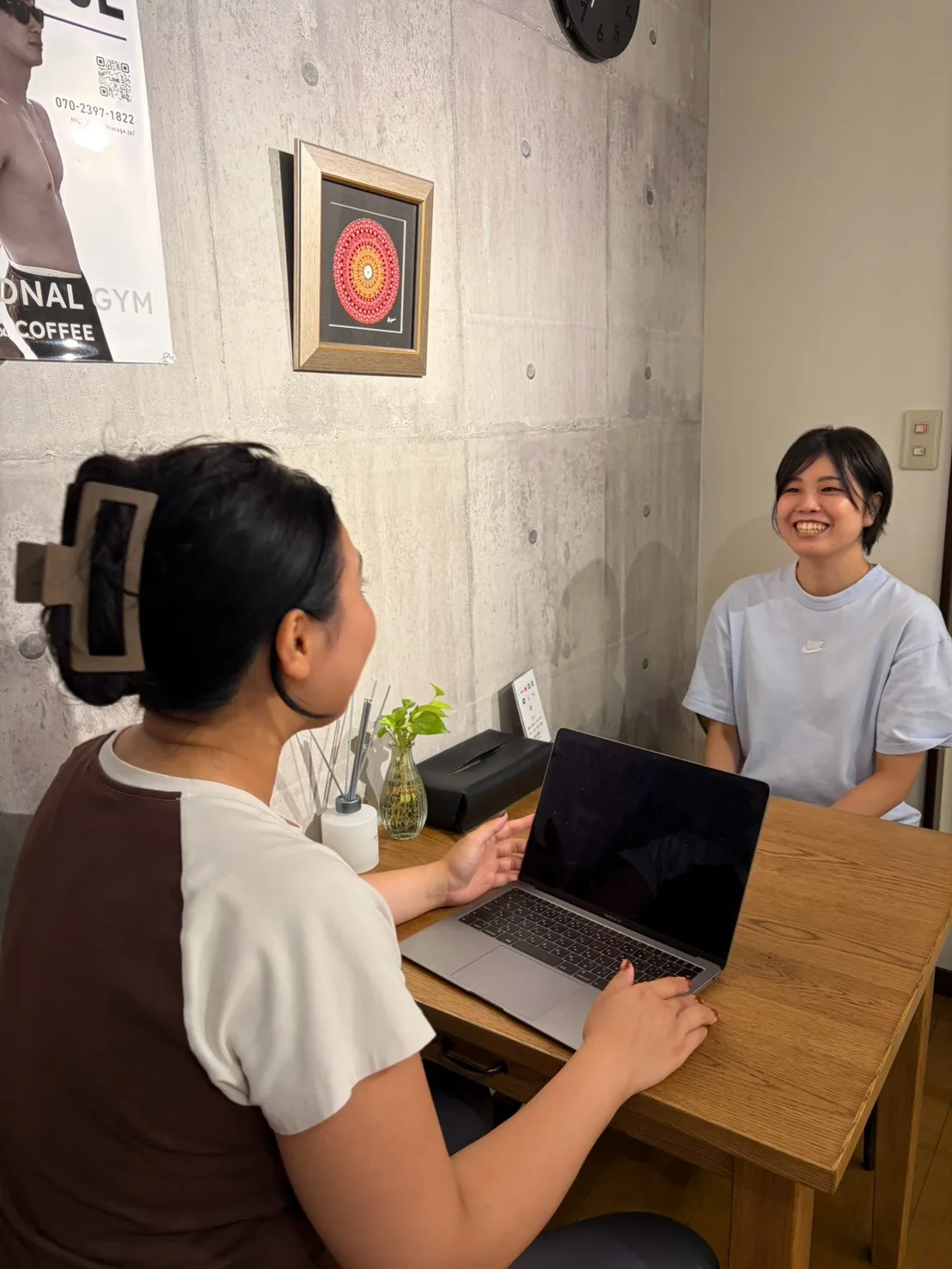 テーブル席でノートパソコンを開き、笑顔で話しながらその日を振り返る様子 — FIT STAGE江坂店
