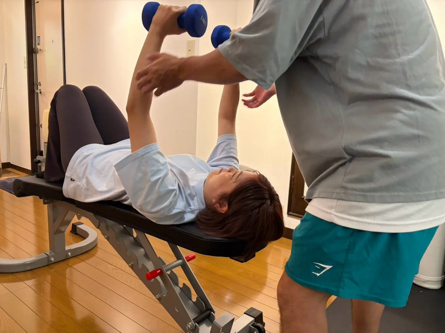 ダンベルプレスをトレーナーが補助する様子 — FIT STAGE江坂店
