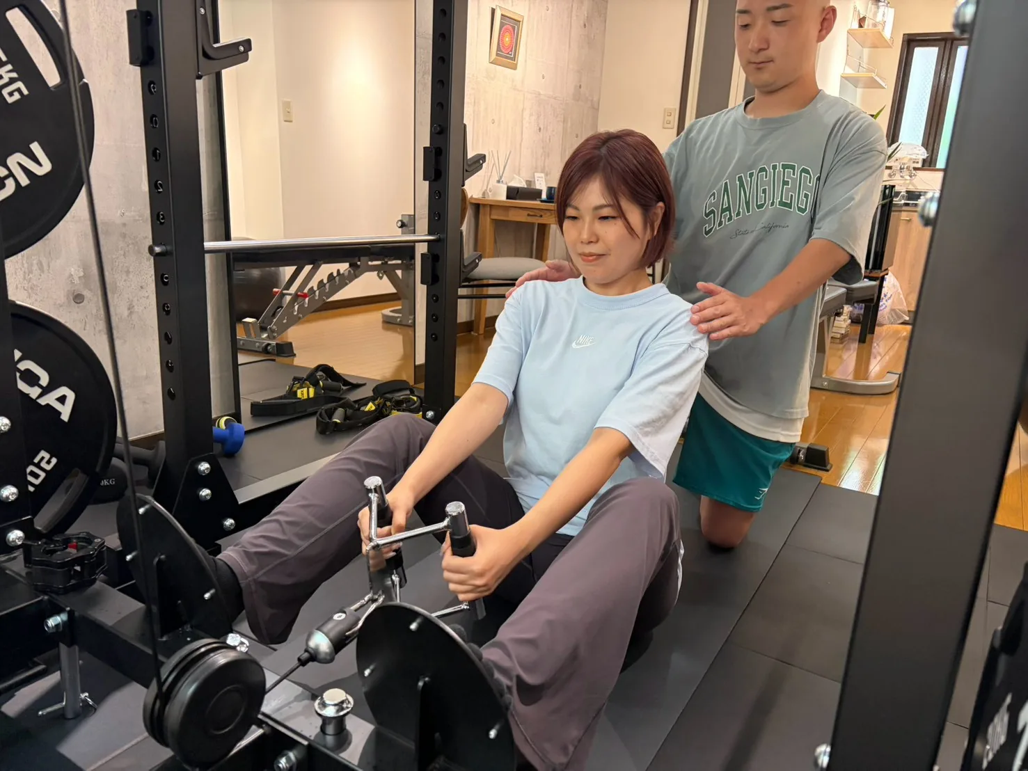 シーテッドロウのフォームをトレーナーが補助する様子 — FIT STAGE江坂店