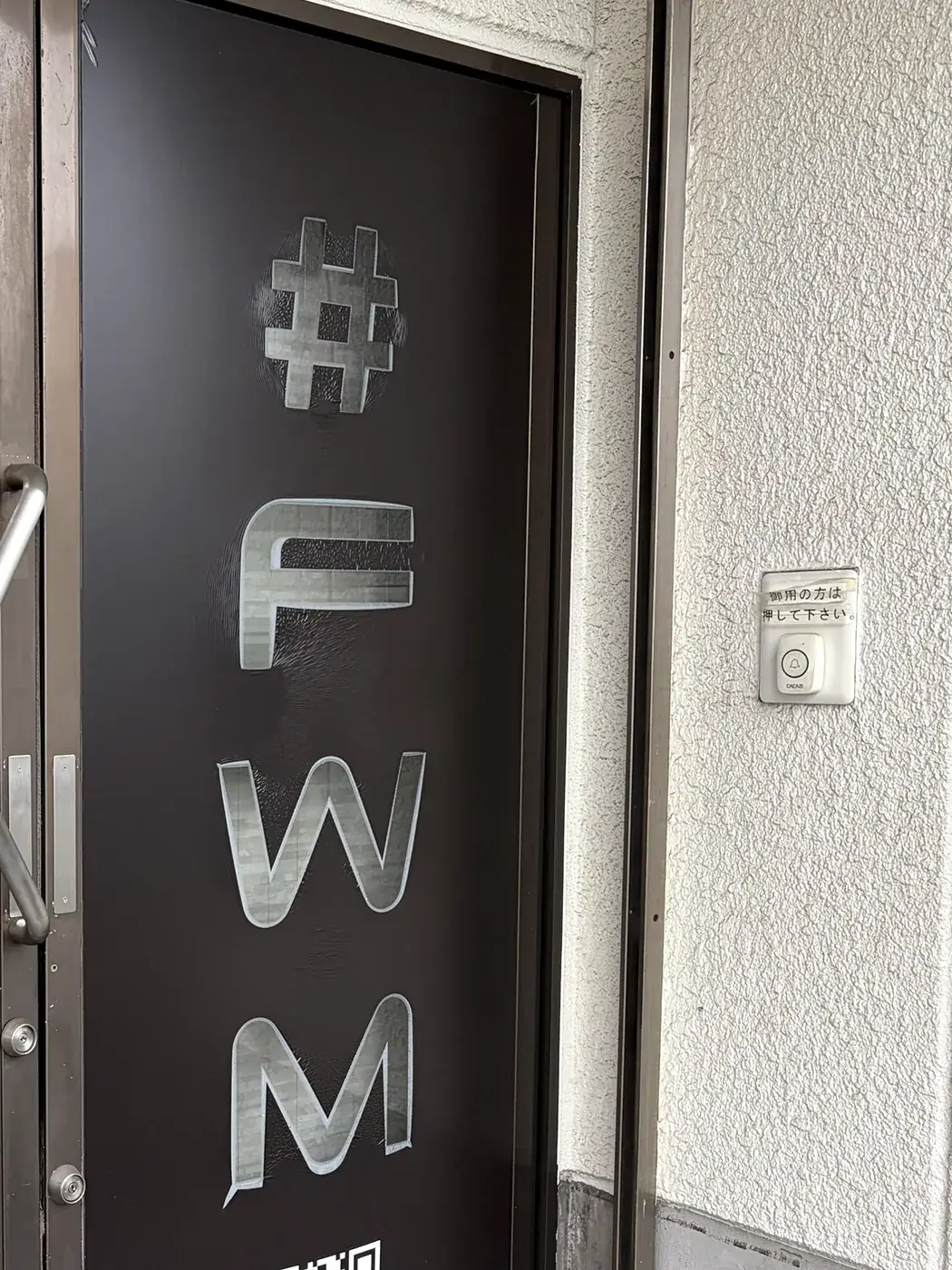 FIT STAGE 庄内店の入口ドア。「#FWM」の表示と呼出ボタンがある
