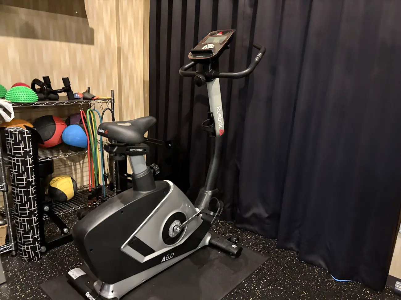 FIT STAGE 曽根城山店のエアロバイクと、メディシンボール・トレーニングチューブ・フォームローラー・バランスディスクを収めたラック